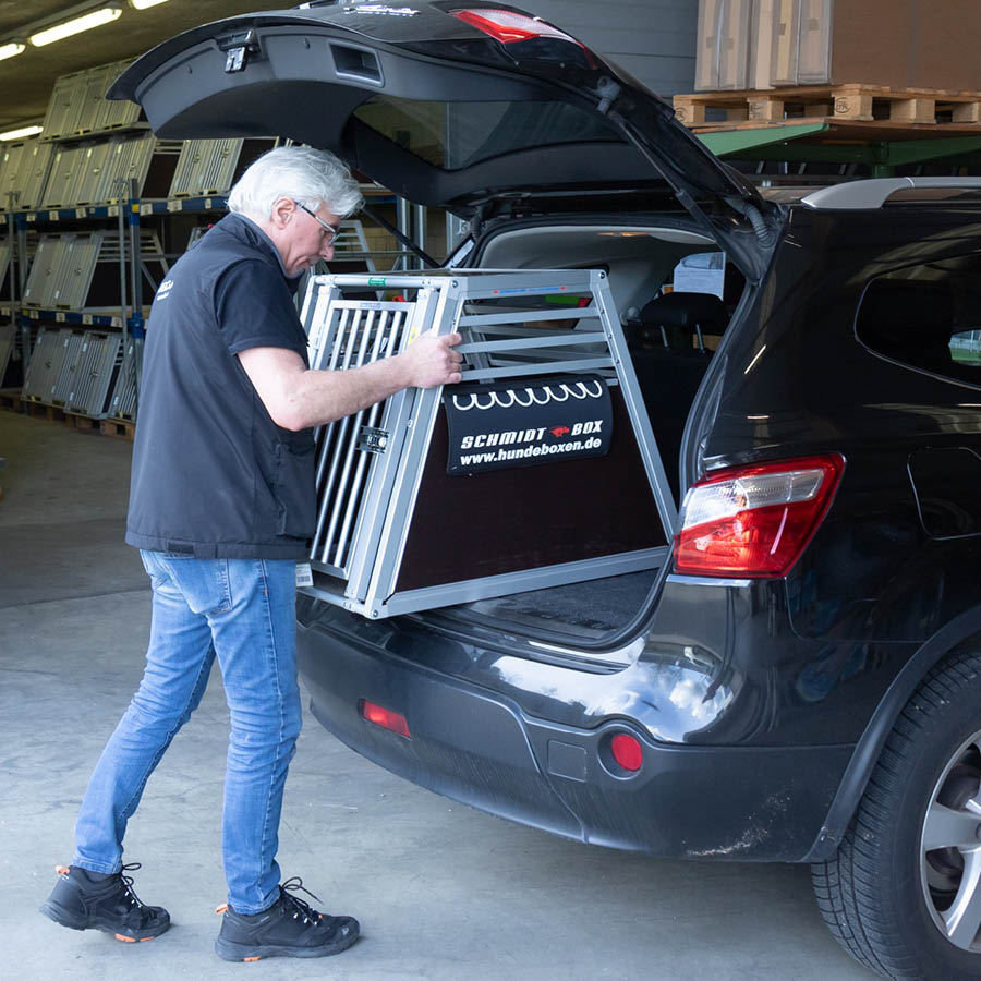 Meiko Mitarbeiter montiert eine Hundebox in einem Auto